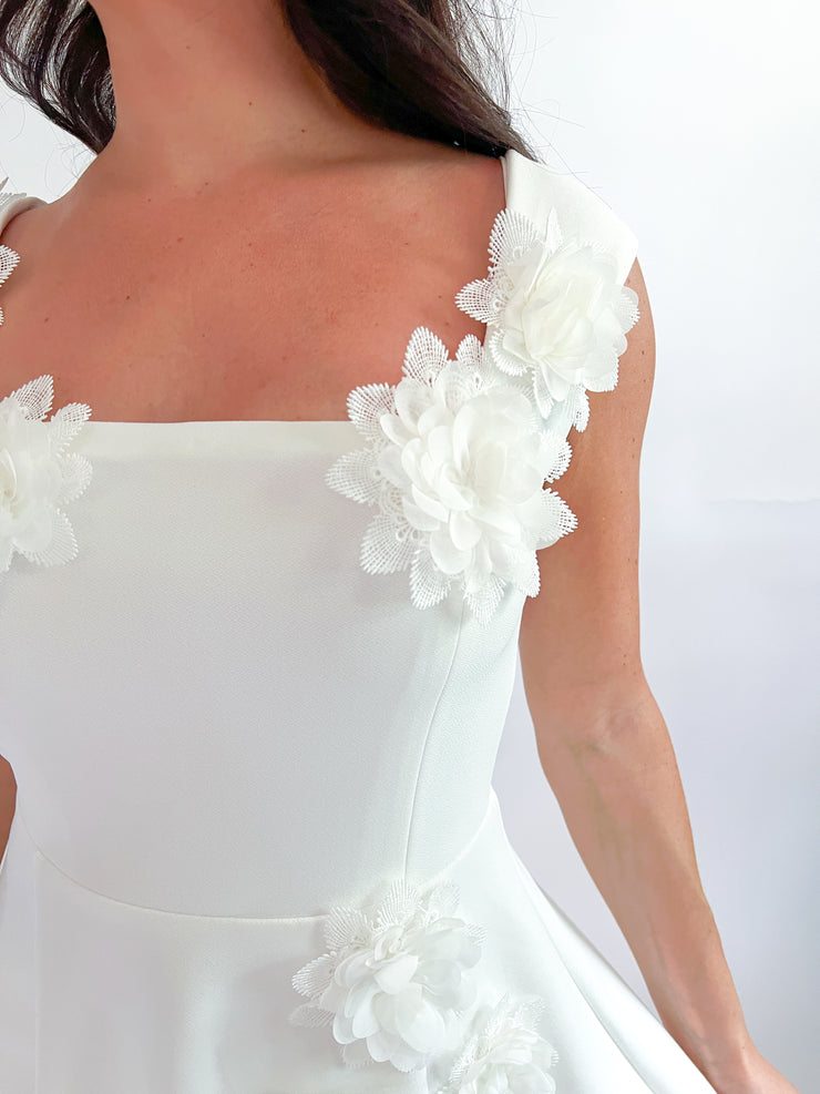 a woman wearing a white dress with flowers