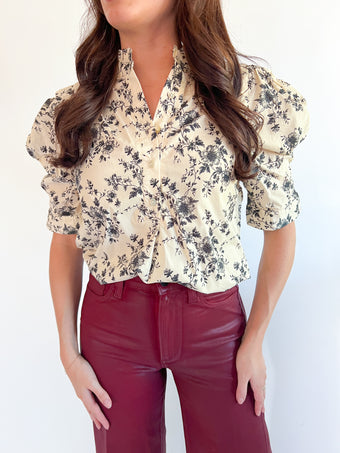 a woman wearing a floral shirt and red pants