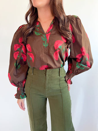 a woman wearing a brown shirt with red flowers