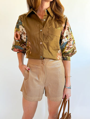 a woman wearing a floral shirt and shorts