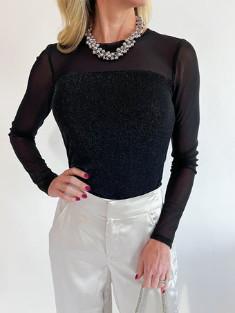 a woman wearing a black top and white pants