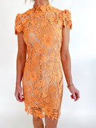 Orange lace cap sleeve mini dress with mock neckline and textured detail